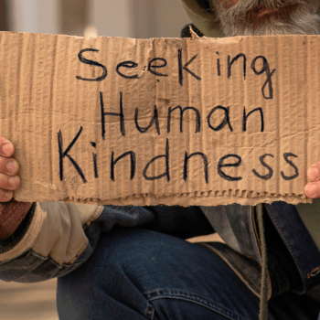 person holding sign saying "seeking human kindness"