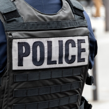 A person wearing a bulletproof vest with the word police across the back. 