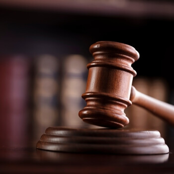 A judge's gavel with law books behind on a shelf behind it. 