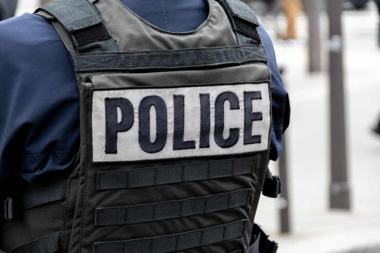 A person wearing a bulletproof vest with the word police across the back. 