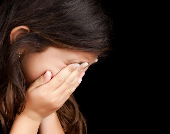 a child holds her face in her hands