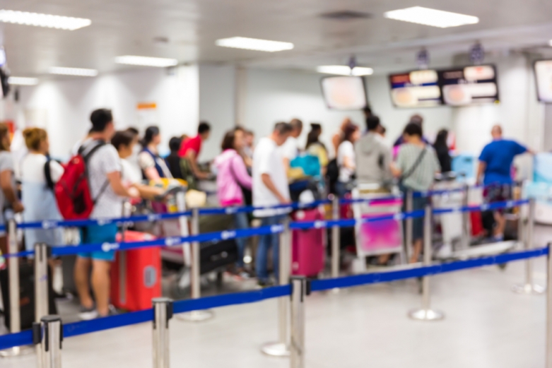 A crowd of people wait in line for security screening at an airport.