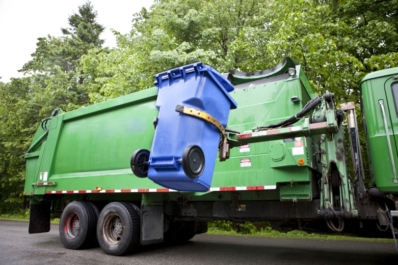 A garbage truck on a tree-lined street.