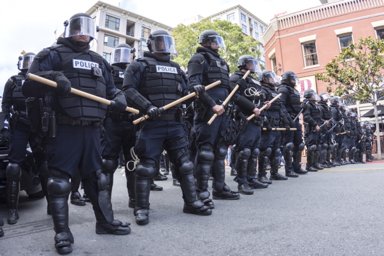 Police in riot gear, holding batons, on a California street