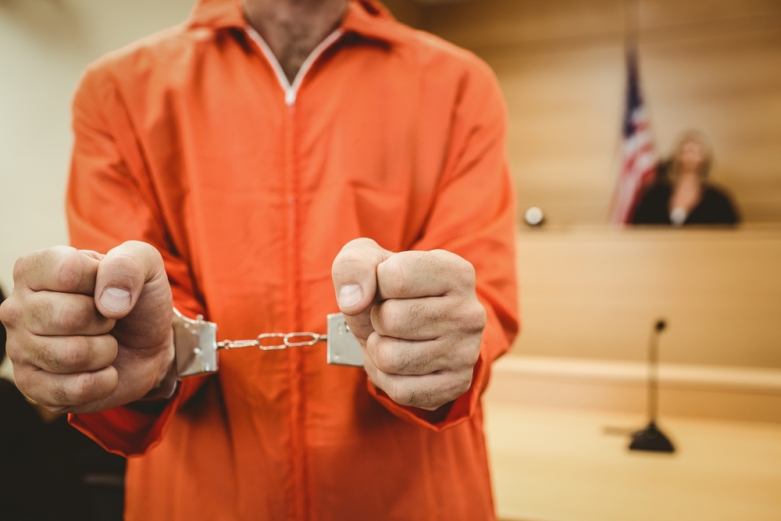 Prisoner in handcuffs clenching fists in the court room