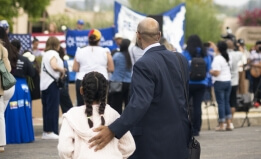 A man and girl at a rally in support of people losing their TPS status.