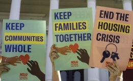 Placards reading "Keep Families Together;" "Keep Communities Whole;" and "End the Housing Crisis"