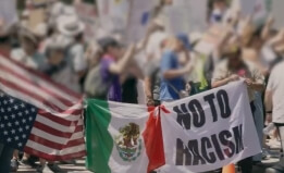 protestors holding the US and Mexico flags and a "No To Racism" sign