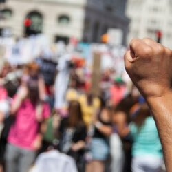raised fist in forground at a protest 